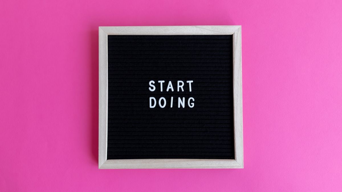 Black letter board with 'Start Doing' motivational text on bright pink background.